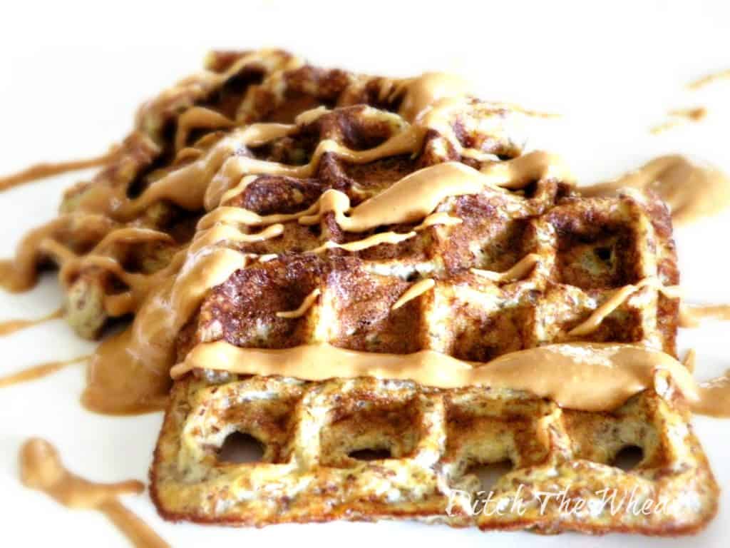 Healthy banana waffles with peanut butter drizzled on them. 