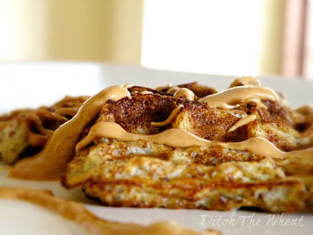 Healthy banana waffles with peanut butter drizzled on them. 