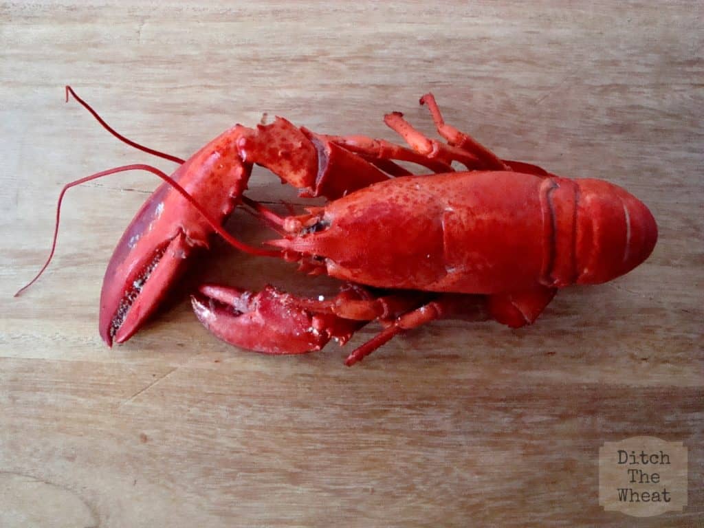 A cooked lobster on a cutting board.
