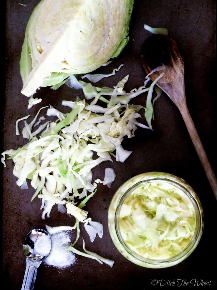 Raw sauerkraut in a jar with raw cabbage and shredded cabbage.