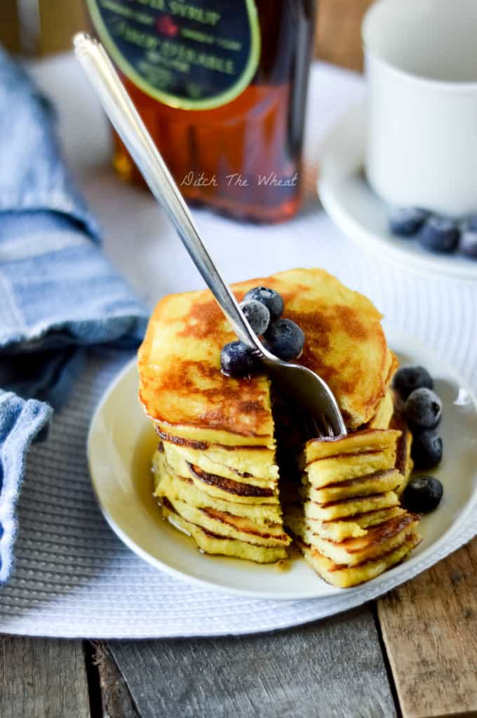 A plate of coconut flour pancakes with fresh blueberries.