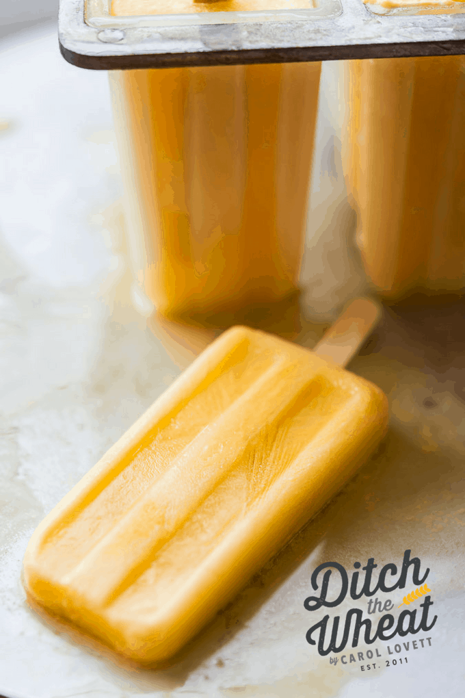 Healthy orange creamsicle popsicles in the popsicle mold with one popsicle out.