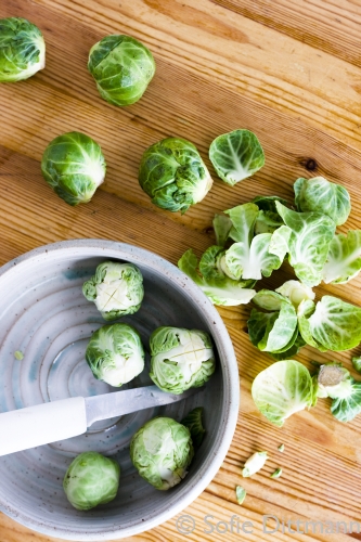 Outer leaves being removed from Brussels sprouts with a bowl.
