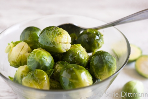A glass bowl filled with cooked Brussels sprouts with balsamic vinegar.