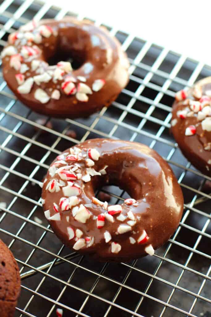 Gluten free peppermint chocolate donuts on a cooling rack.