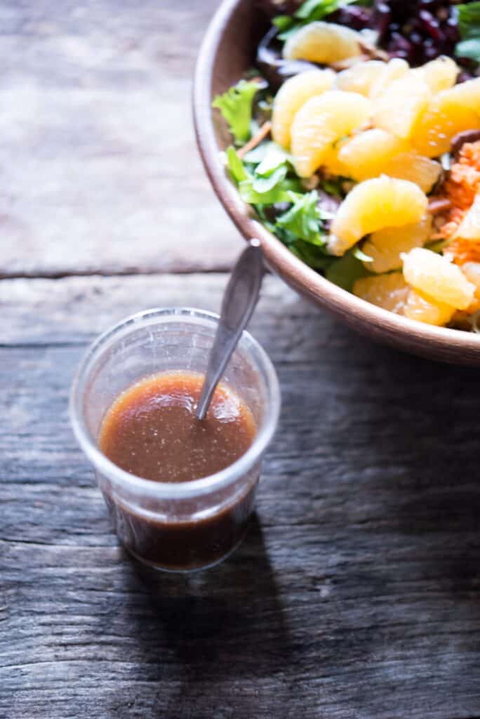 Maple Balsamic Dressing in a glass jar beside a harvest salad.