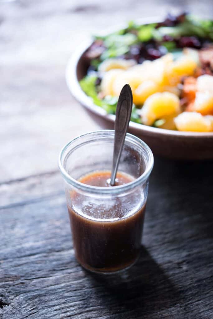 Maple Balsamic Dressing in a glass jar beside a harvest salad.