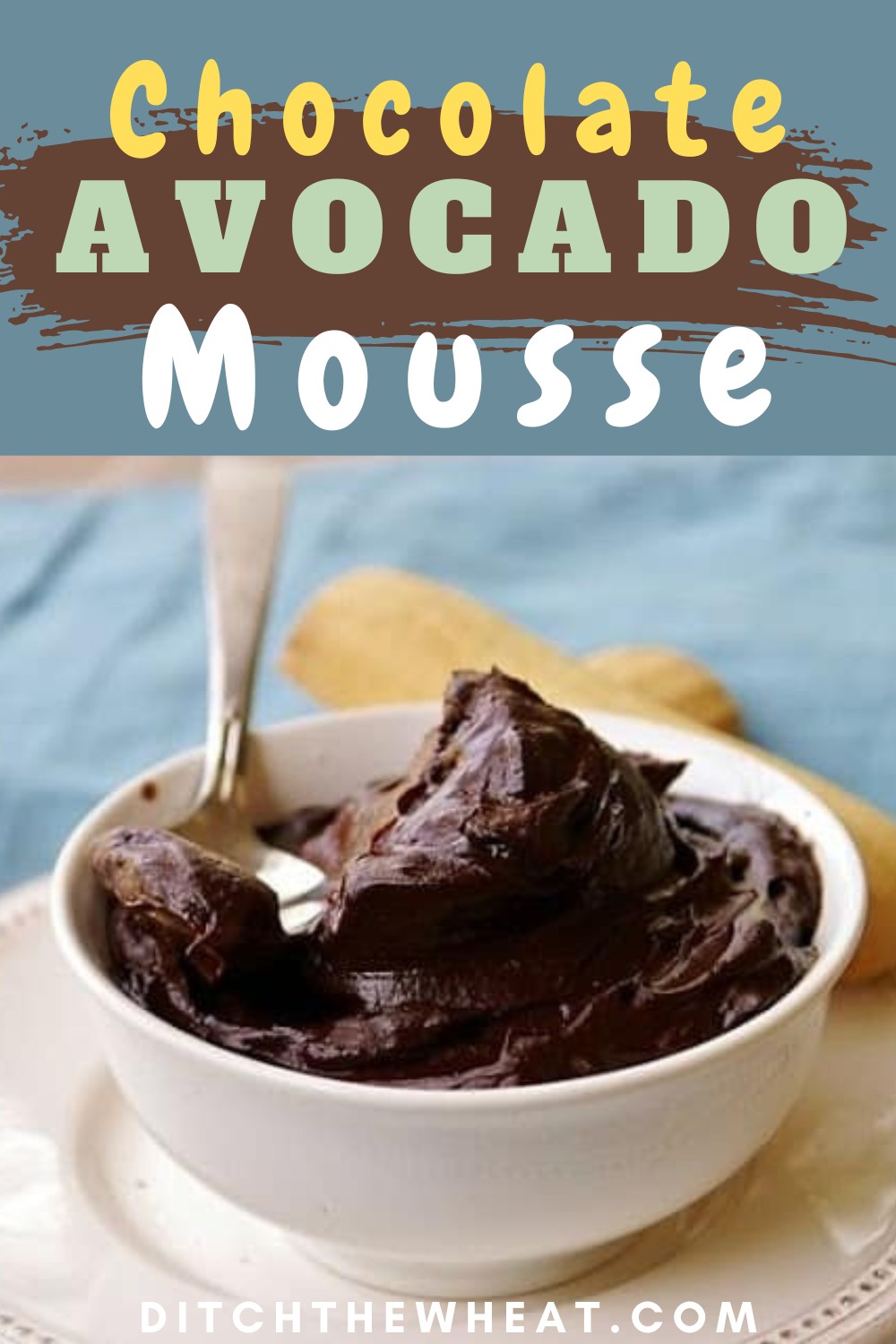 A white bowl filled with chocolate avocado mousse with a spoon and a cookie.