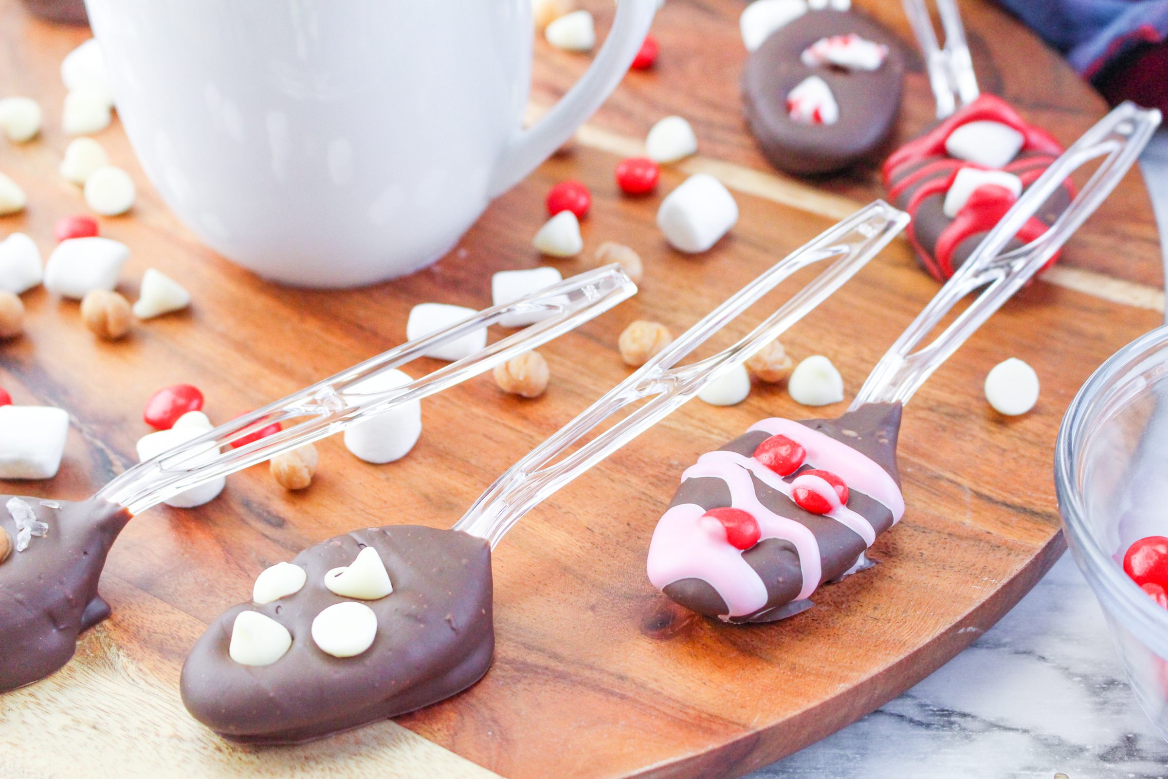 5 hot chocolate spoons on a wooden background with a white mug.