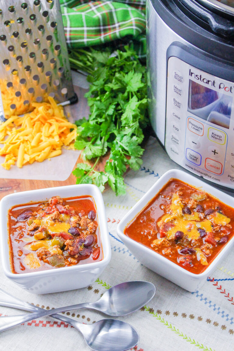 An instant pot with two bowls of ground turkey chili with spoons.