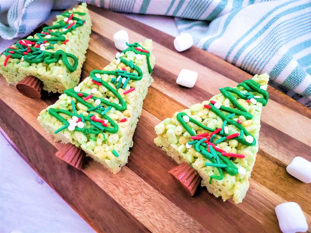 Rice Krispie Christmas Trees on a wooden board.