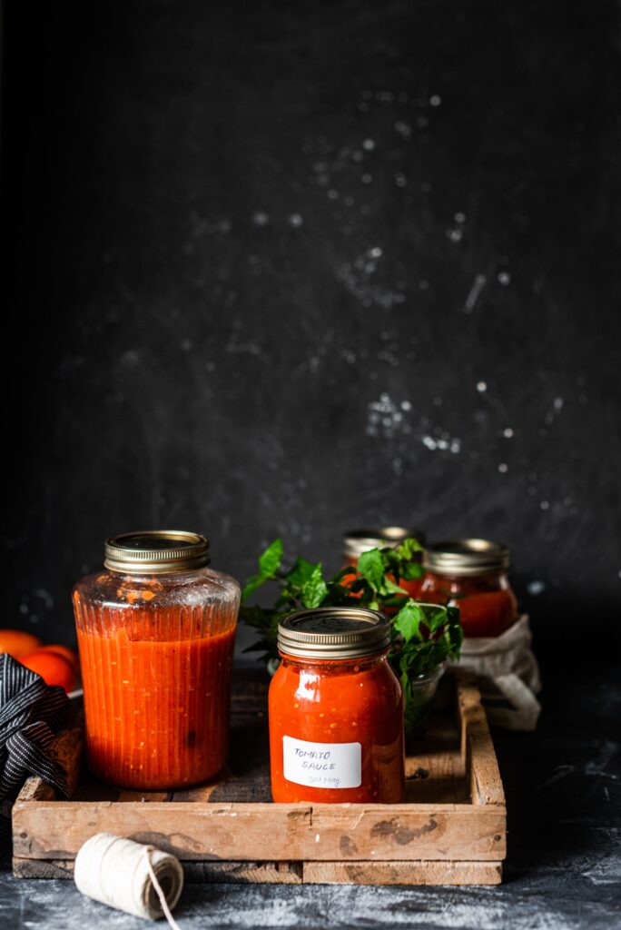 Is tomato sauce gluten free? Glass jars of tomato sauce in a wooden tray.
