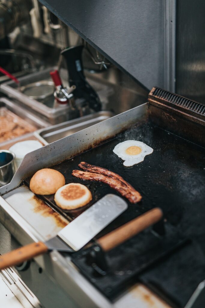 Is Bacon Gluten free? An image of bacon, eggs, and a bun being grilled. 