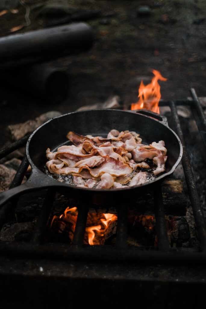 Is Bacon Gluten free? Bacon cooking in a skillet over an open fire. 