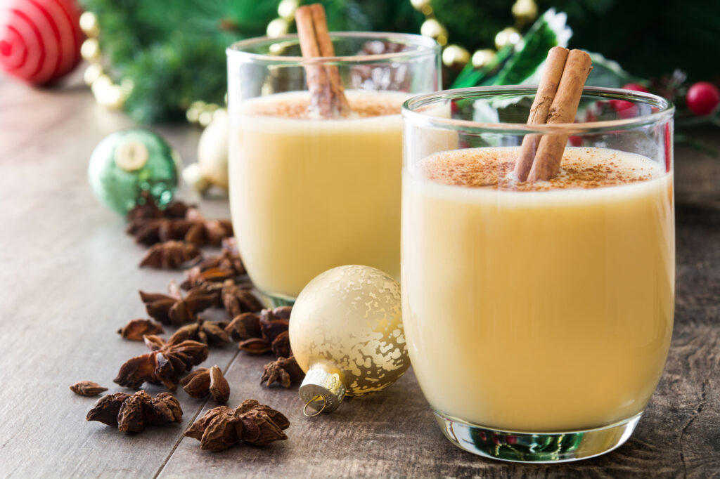 Is Eggnog Gluten Free? Two glasses filled with eggnog with cinnamon sticks and holiday decor.