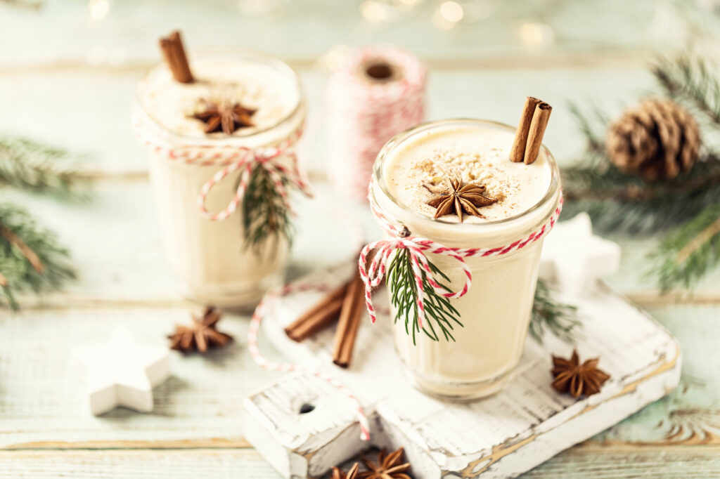 Is Eggnog Gluten Free? Two glasses full of eggnog with cinnamon sticks and holiday decor.