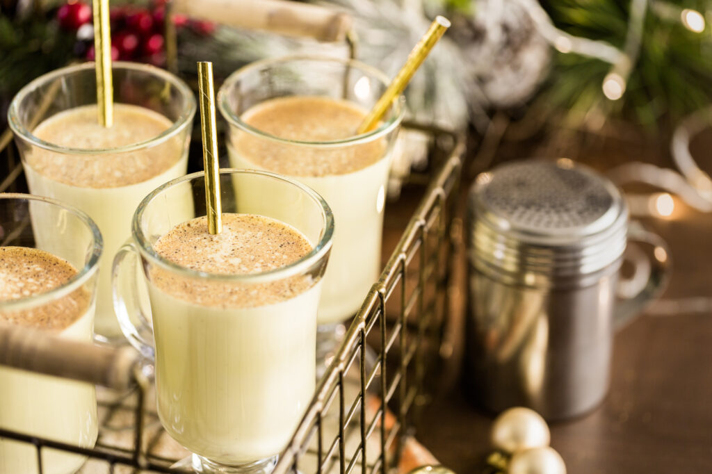 Is Eggnog Gluten Free? A wire basket filled with 3 glass of eggnog with gold straws.