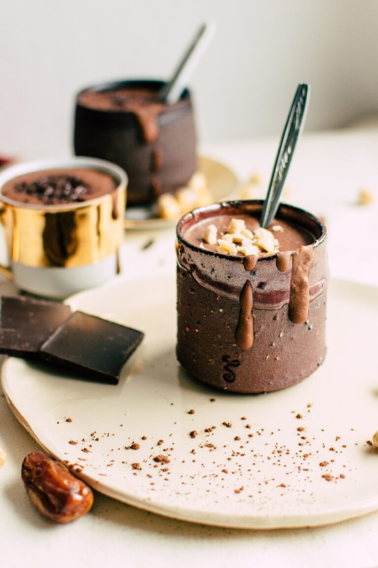 Hot chocolate in a mug with a spoon with hot chocolate in the background.
