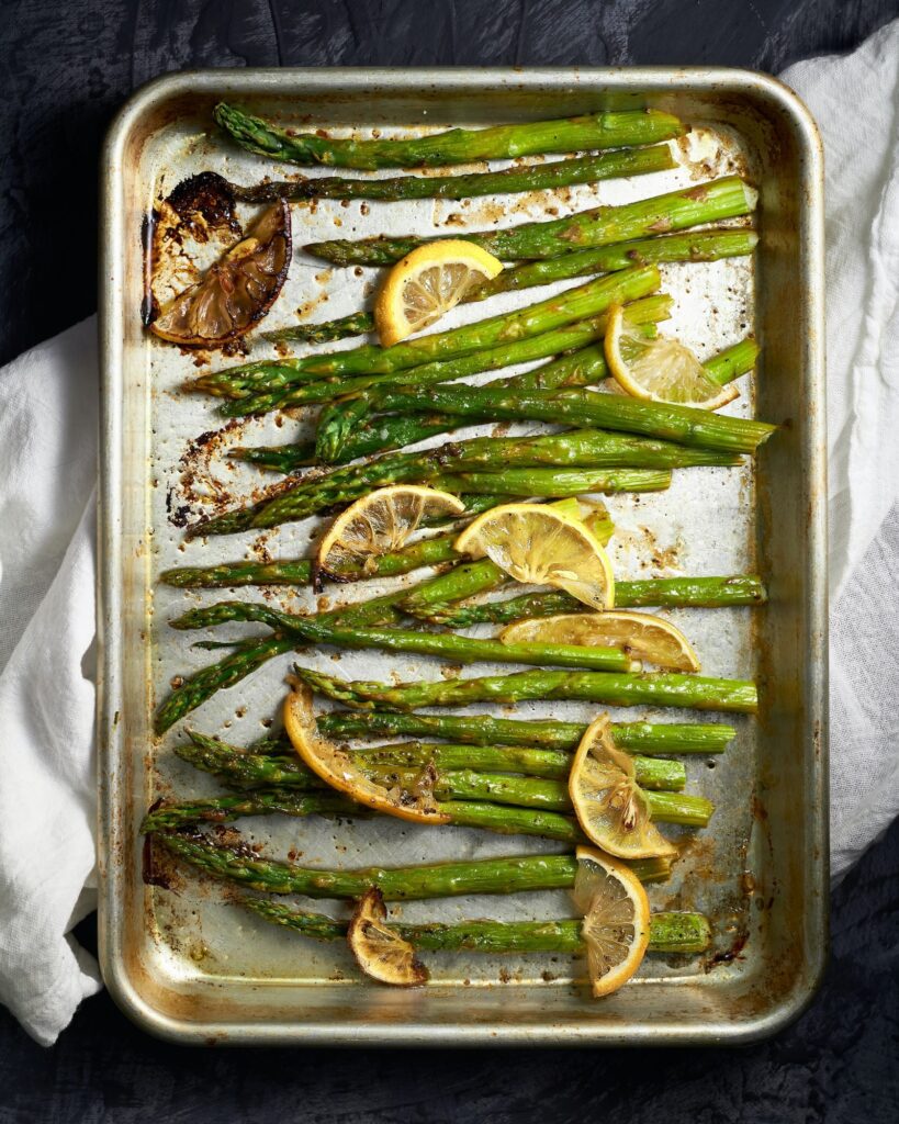 Roasted asparagus with lemon slices on a baking sheet.