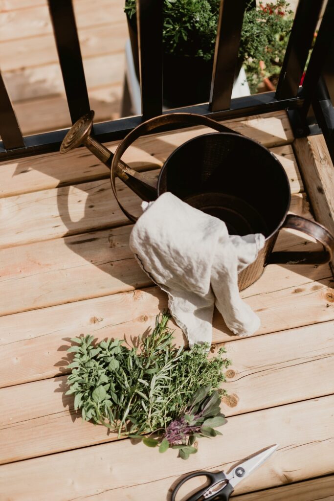 Fresh cut herbs laying on the deck with a watering can. 