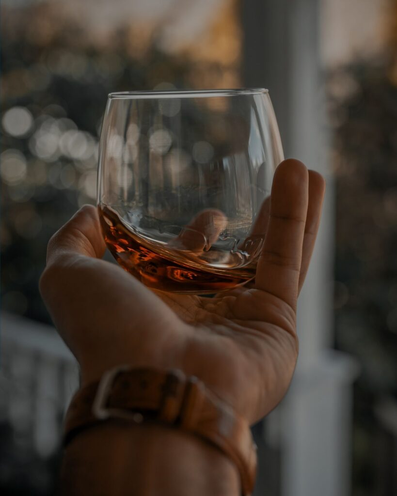 A hand holding a glass of bourbon.