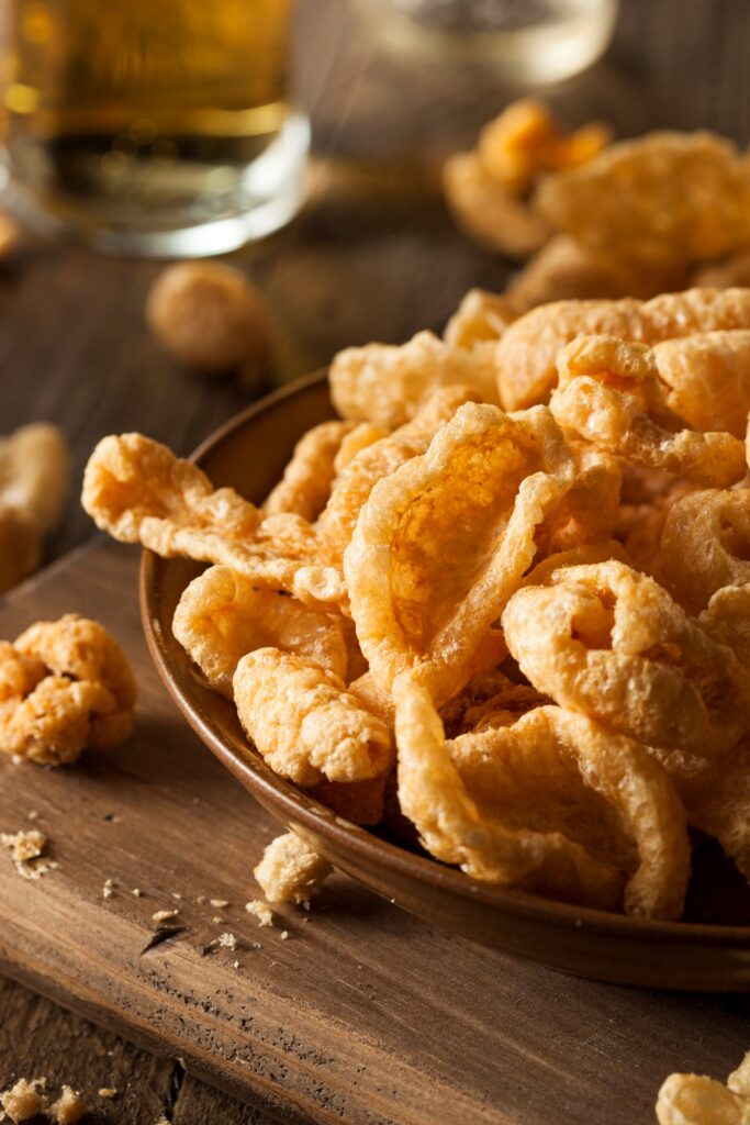 A bowl of pork rinds with a wooden background.