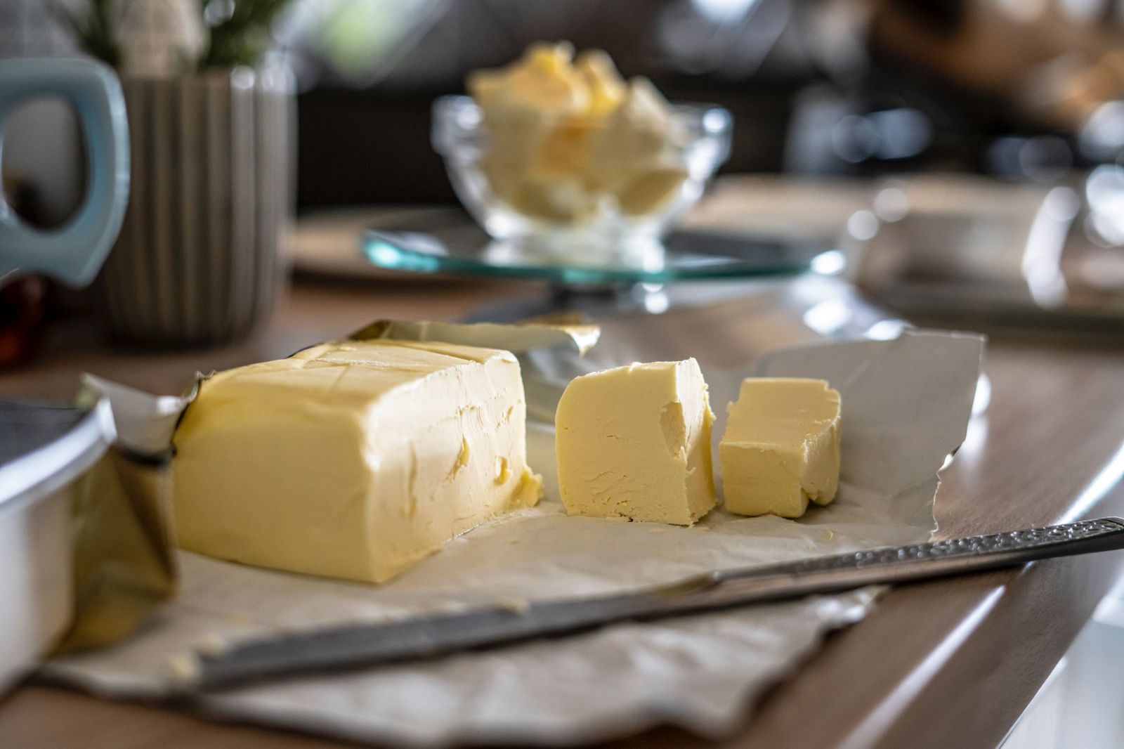 A brick of butter cut into smaller pieces with a knife.