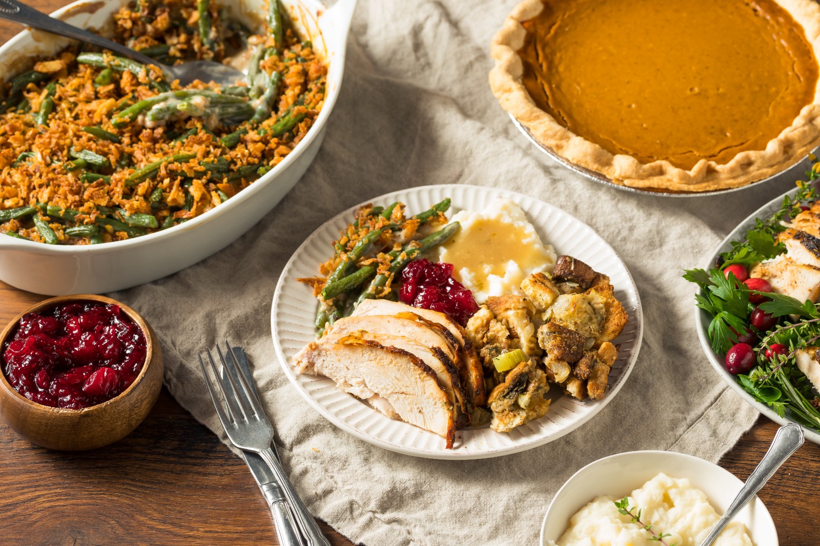 Sides dishes with a plate filled with turkey, green bean casserole, mashed potatoes, and stuffing.