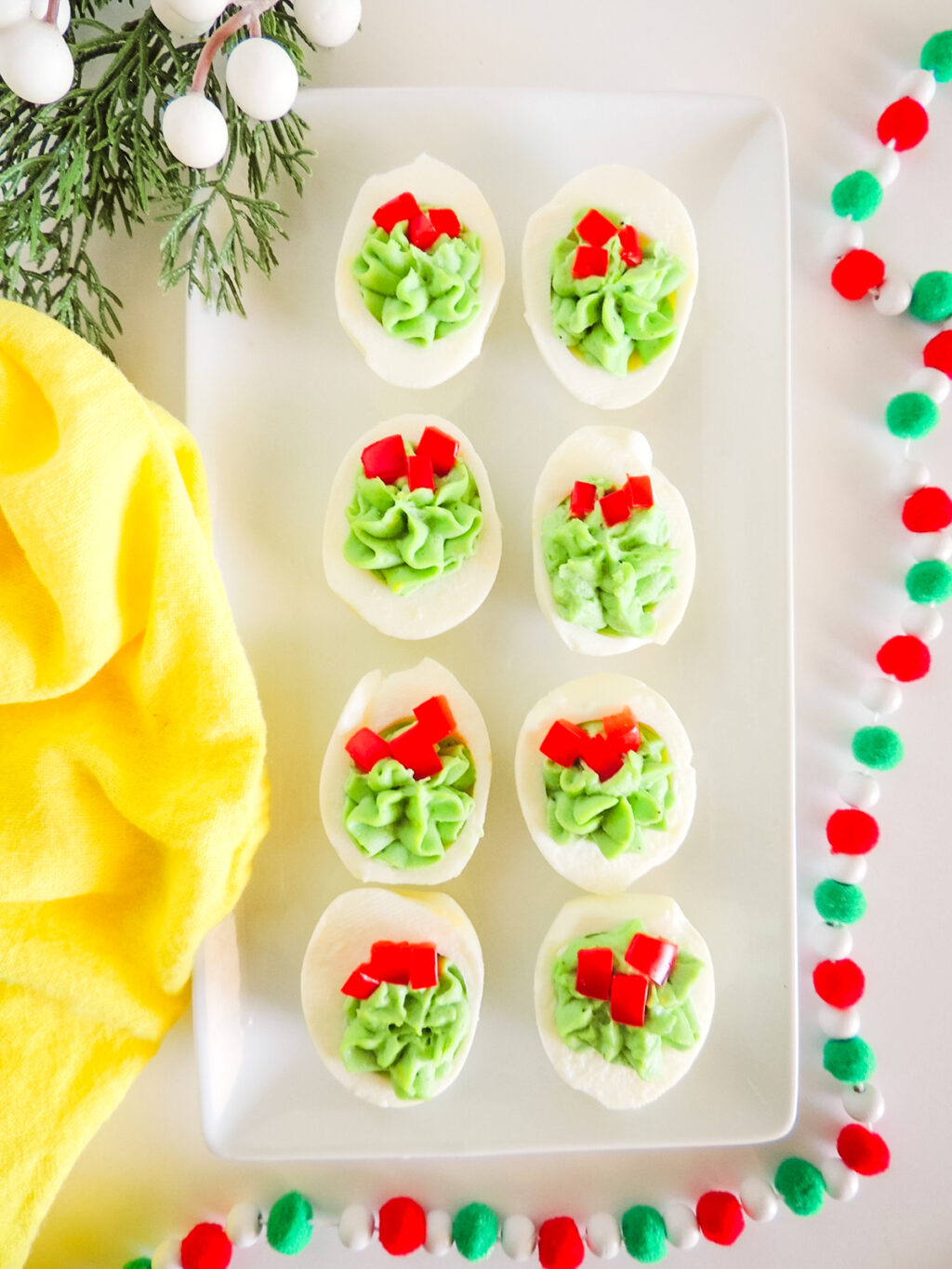 A tray of Christmas deviled eggs with a yellow towel.