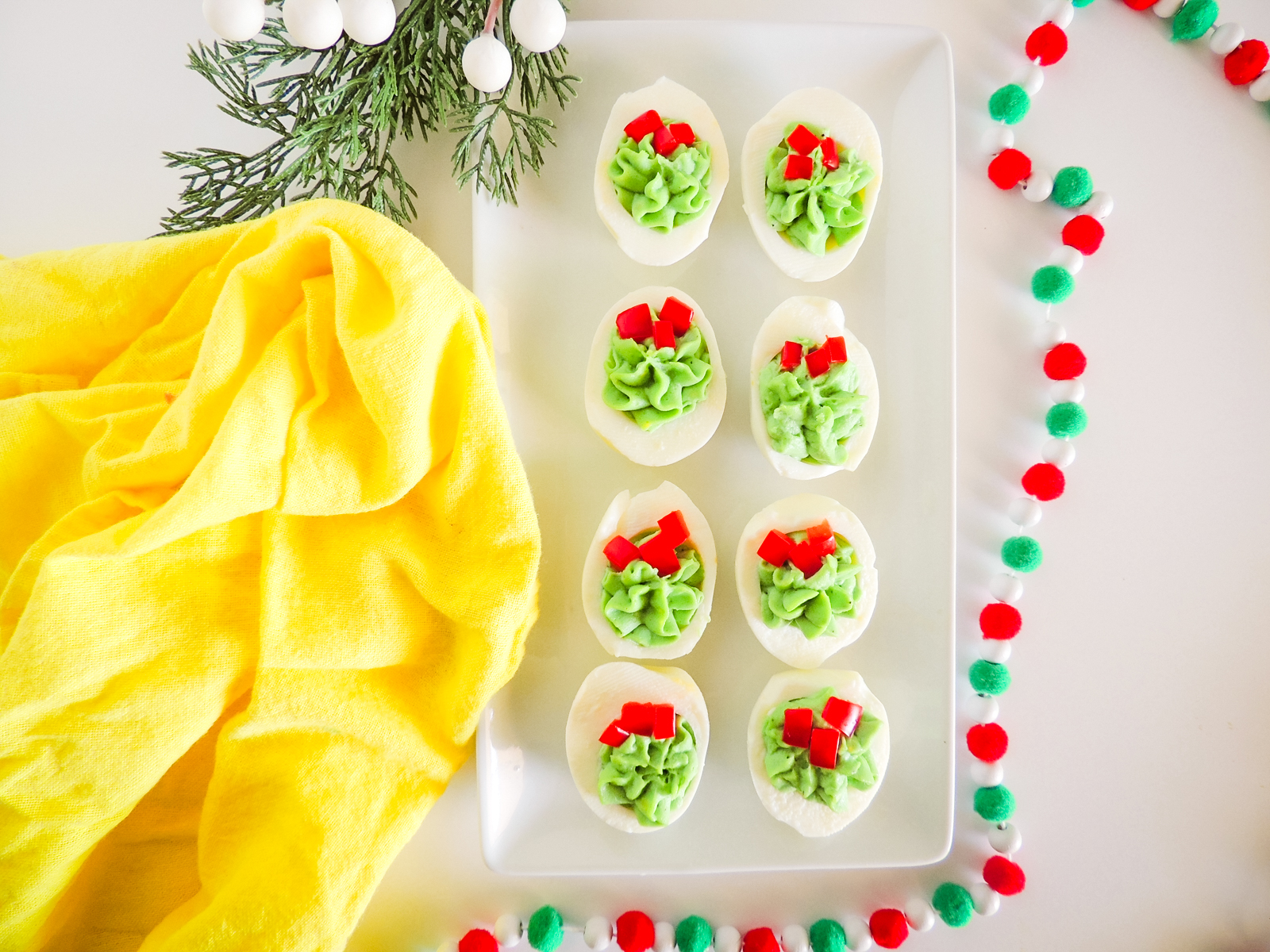 A tray of Christmas deviled eggs with a yellow towel.