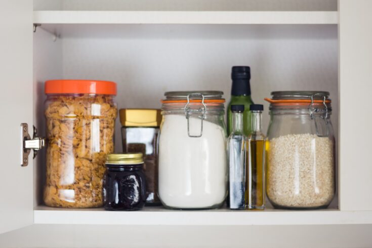 A cupboard with various pantry items in jars including gluten free baking powder.