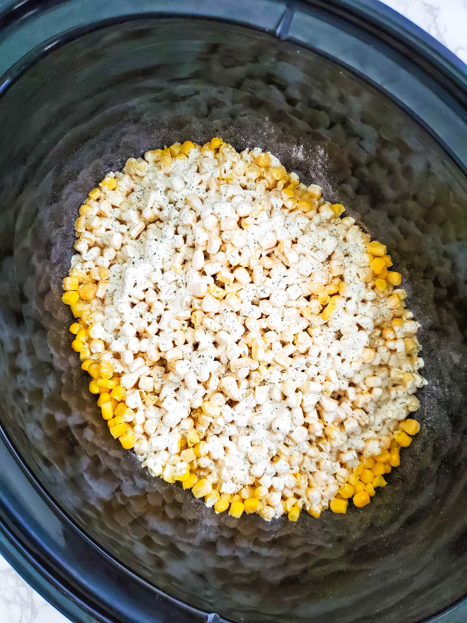 Ranch seasoning sprinkled all over the frozen corn in a Crockpot.