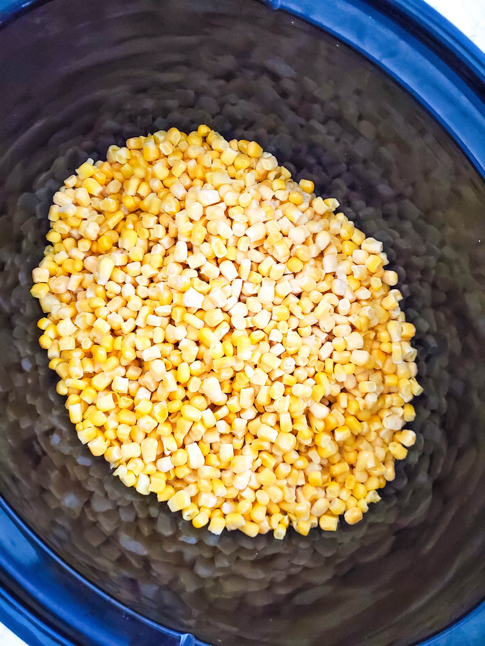 A Crockpot filled with frozen corn.