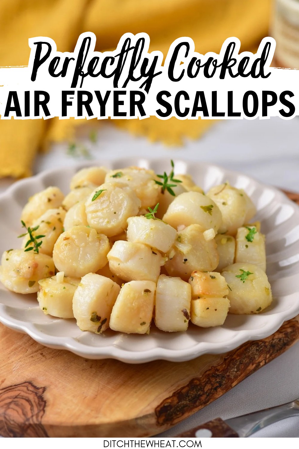 A white plate with air fryer scallops on a wooden cutting board and a yellow napkin in the background.