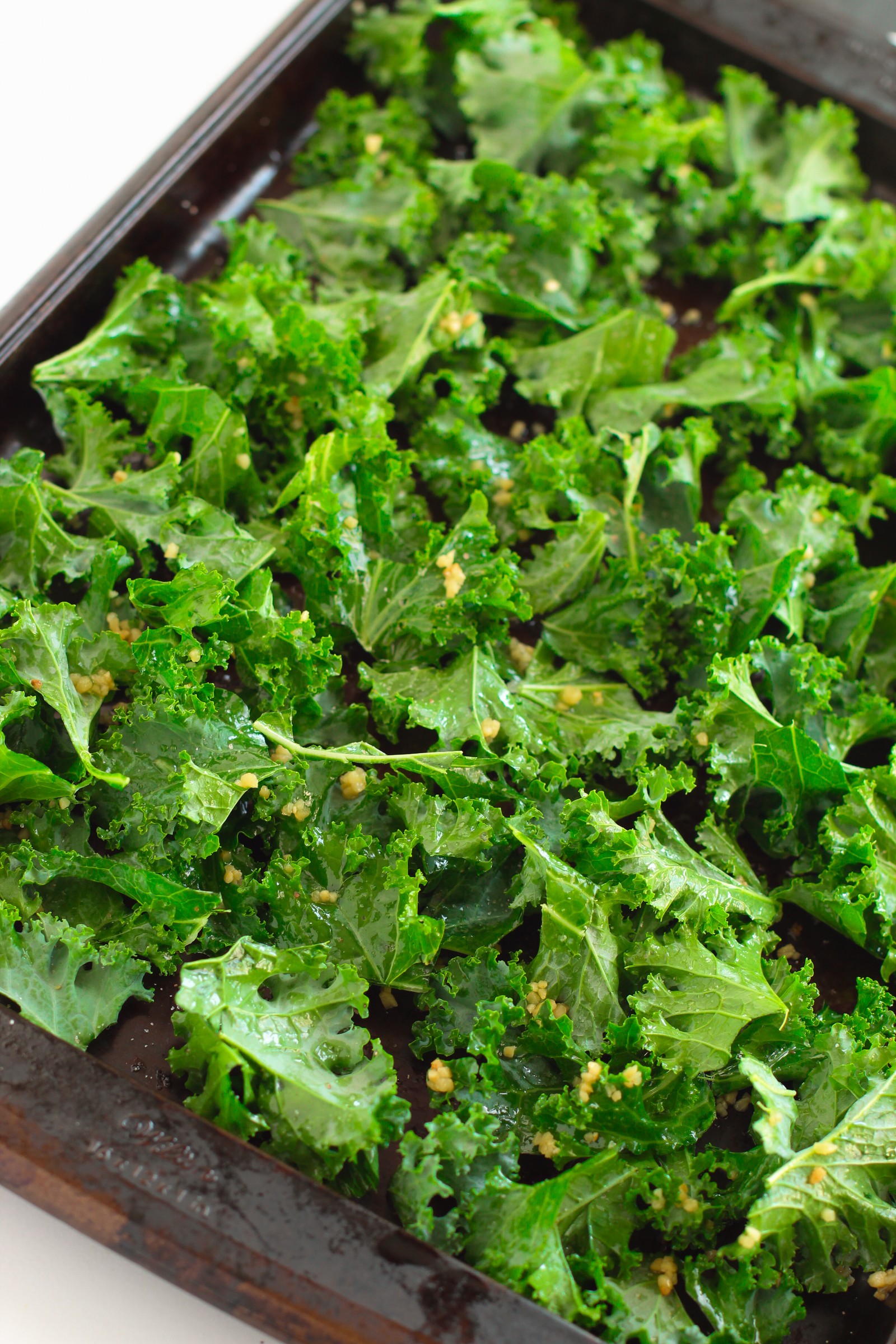 Raw kale on a baking sheet to be baked.