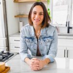 Gina Matsoukas wearing a jean jacket in a kitchen.