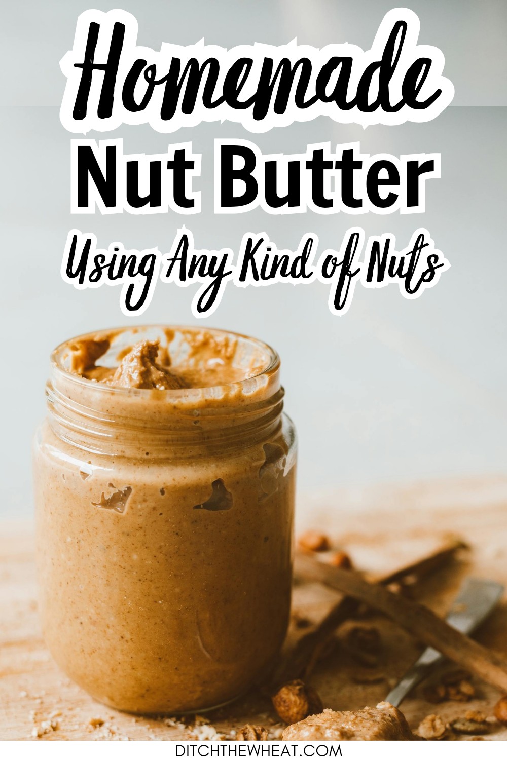 A glass jar filled with homemade peanut butter and a spoon with peanut butter on it.