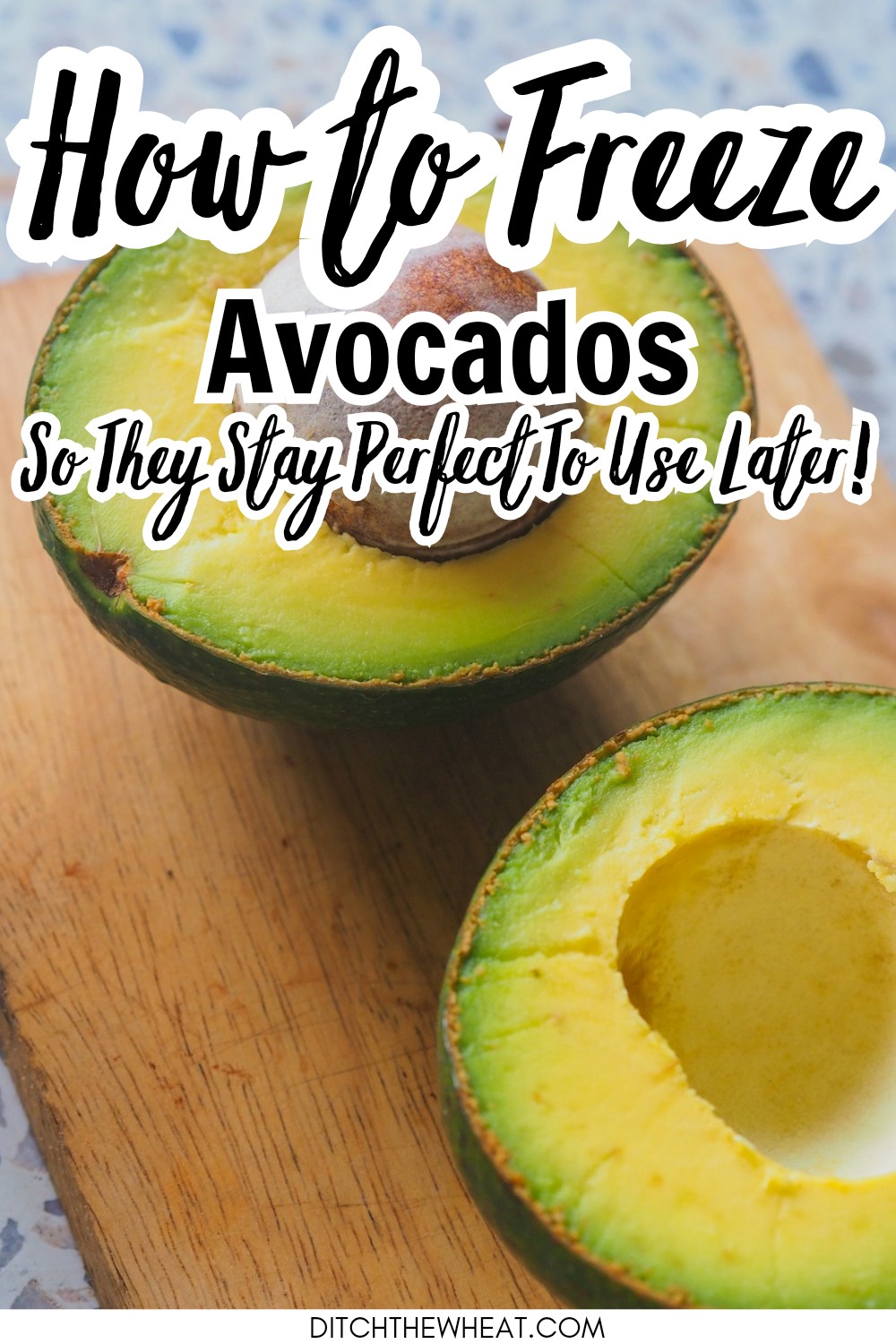 An avocado cut in half on a wooden cutting board.