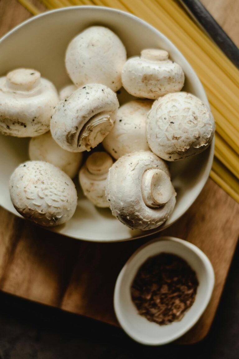 A white bowl filled with mushrooms and a small bowl with spice.