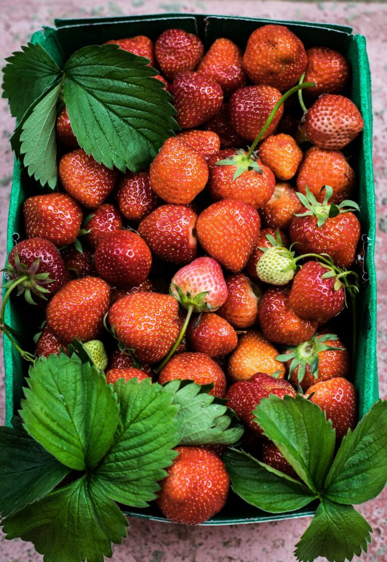 A green basket filled with fresh strawberries.