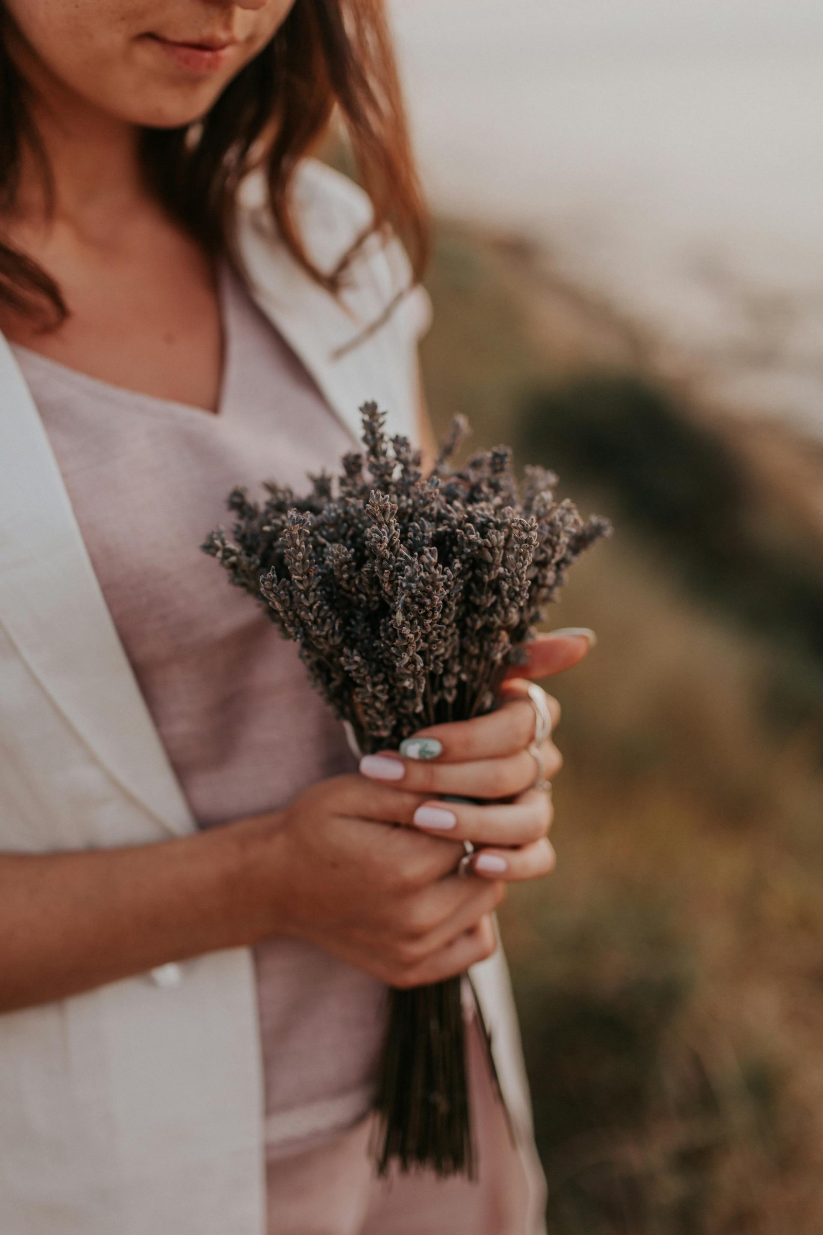 A woman holding a bundle of lavender outside.