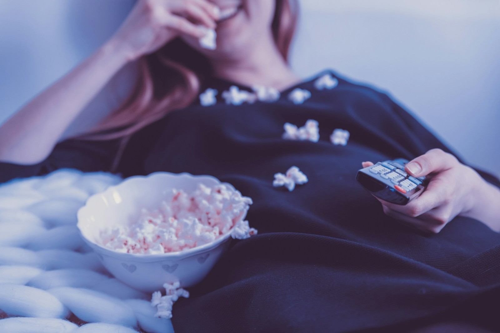 A woman eating popcorn laying down.