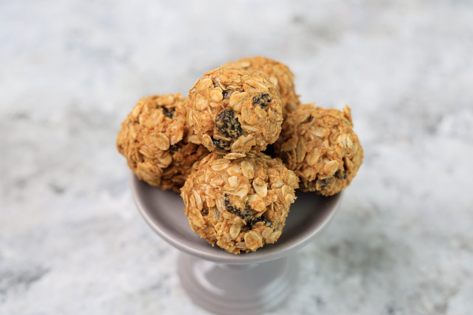A grey dessert stand with a couple of oatmeal raisin balls.