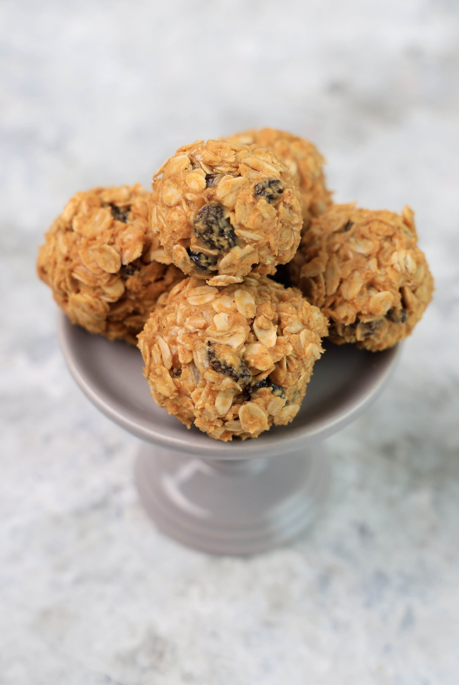 A grey dessert stand with a couple of oatmeal raisin balls.