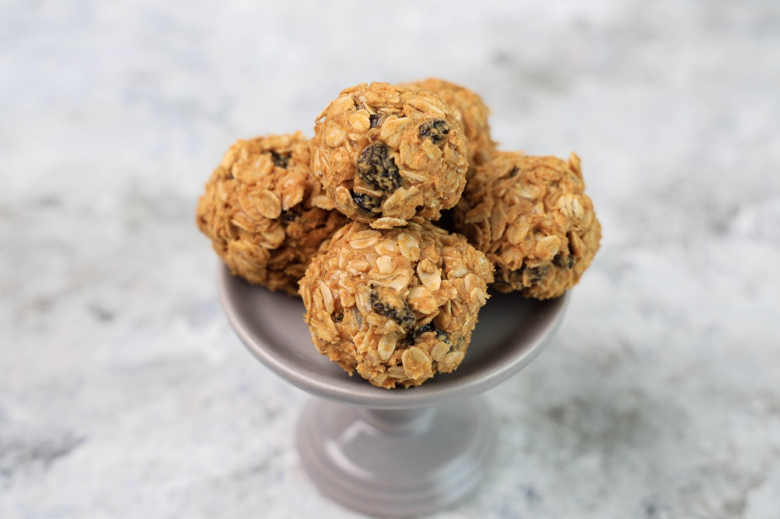 A grey dessert stand with a couple of oatmeal raisin balls.