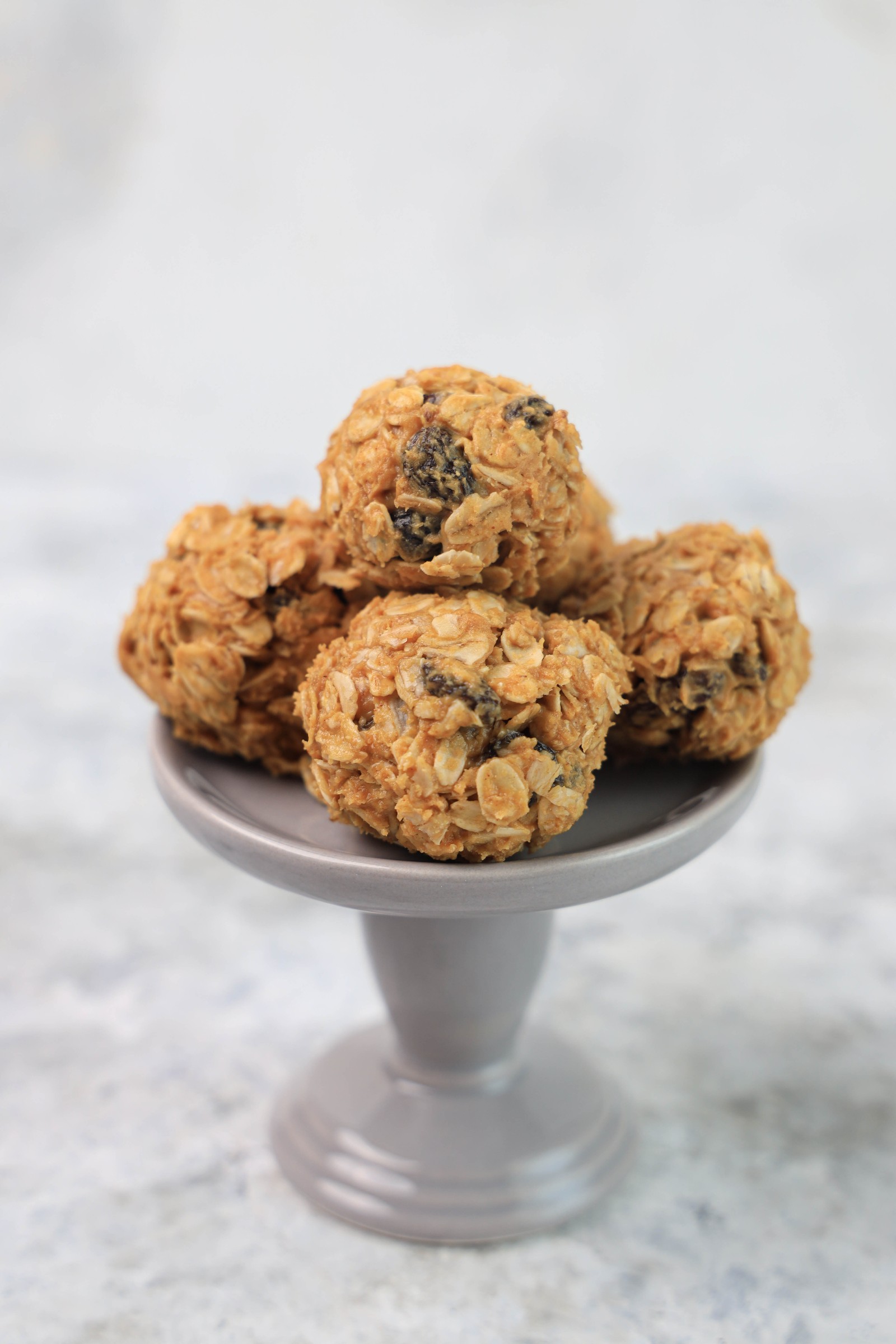 A grey dessert stand with a couple of oatmeal raisin balls.