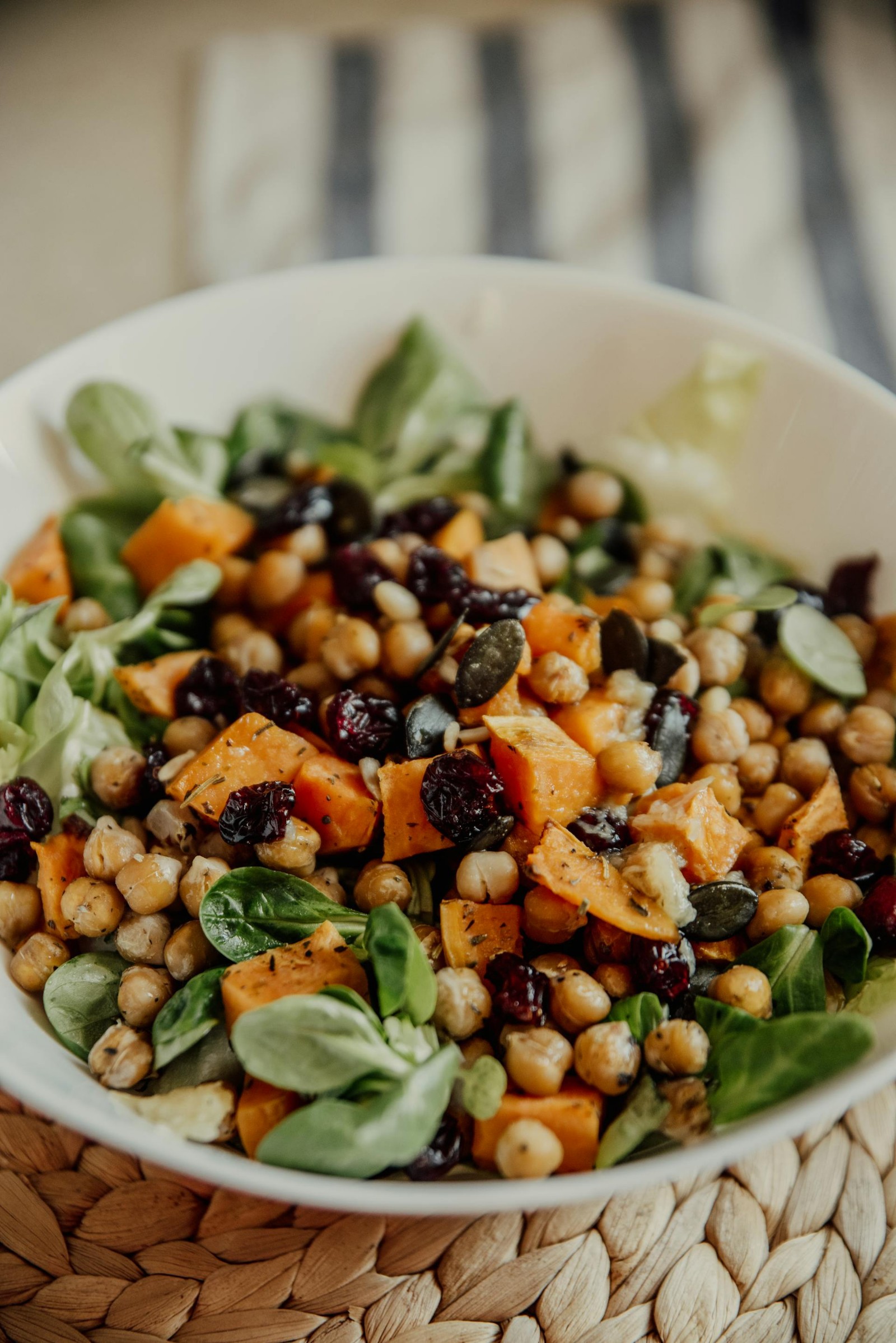 A bowl of salad with chickpeas, lettuce, and black olives.