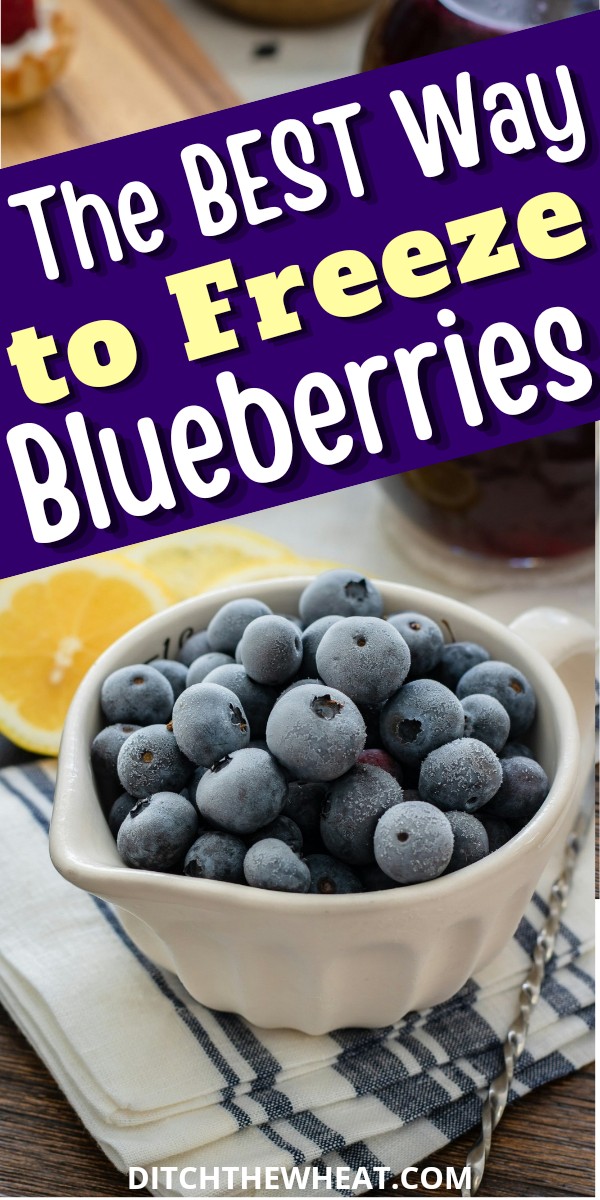 A white bowl filled with frozen blueberries and lemon slices in the background.