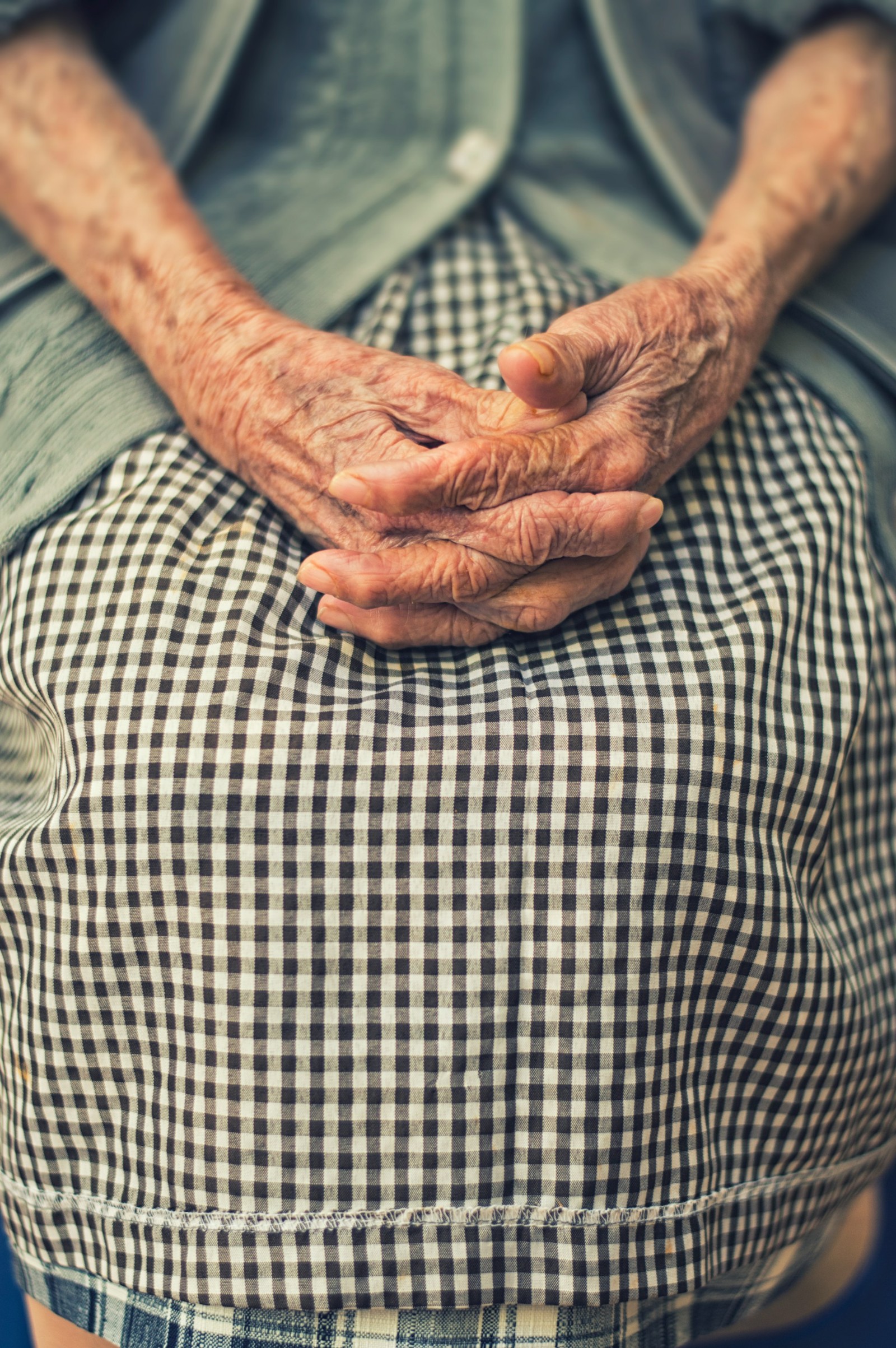 An image of an elderly woman with her hands touching.