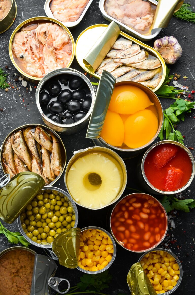 Various Canned Foods with the lids open on a dark background.